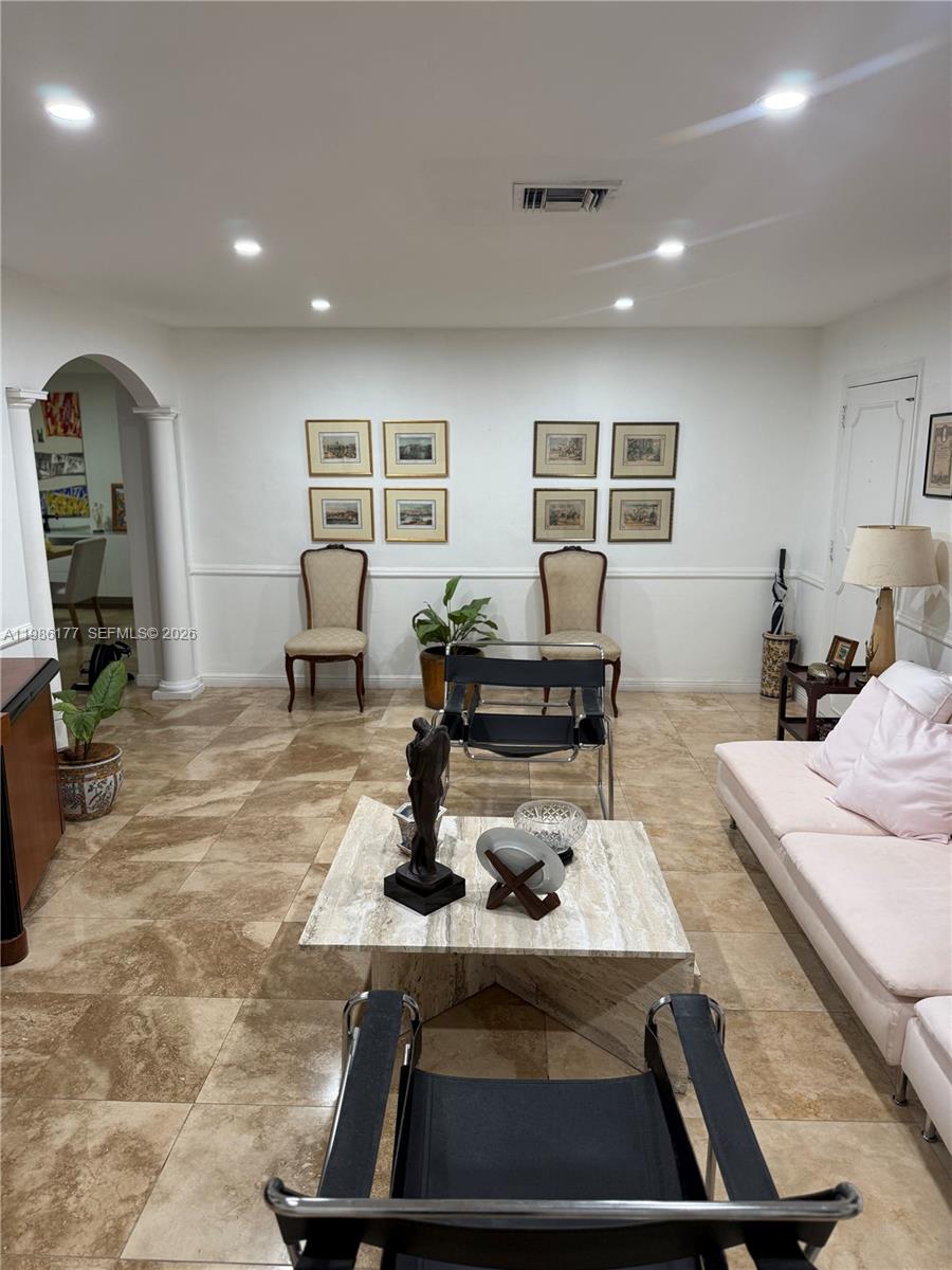A living room features tile flooring, a light-colored sofa, two black chairs, and framed wall art — 1208 Bird Rd, Coral Gables FL 33146, CORAL GABLES, FL