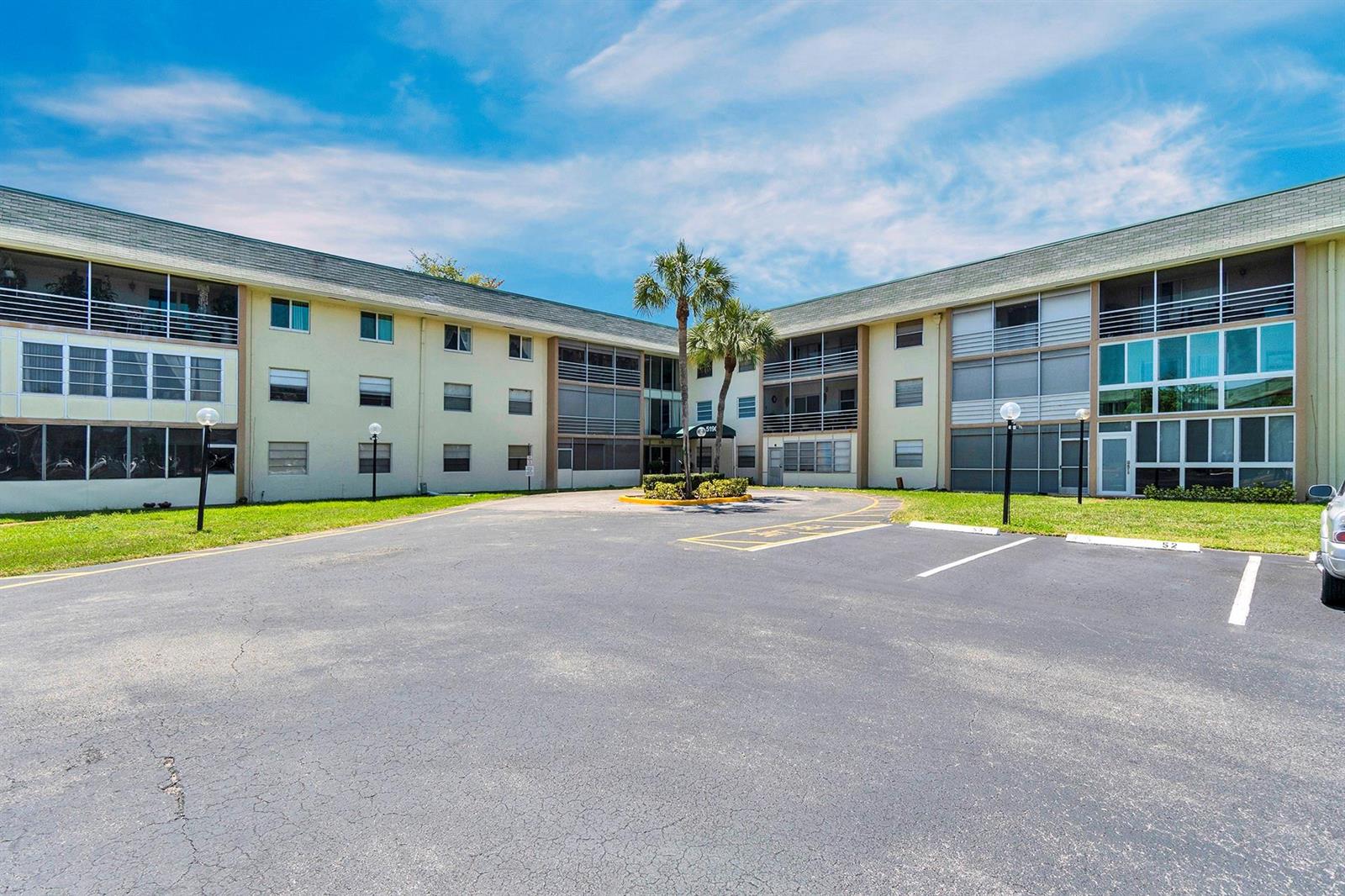 A three-story apartment building with a paved parking lot and palm trees in front — 5190 E Sabal Palm Boulevard # 304, Tamarac FL 33319, TAMARAC, FL