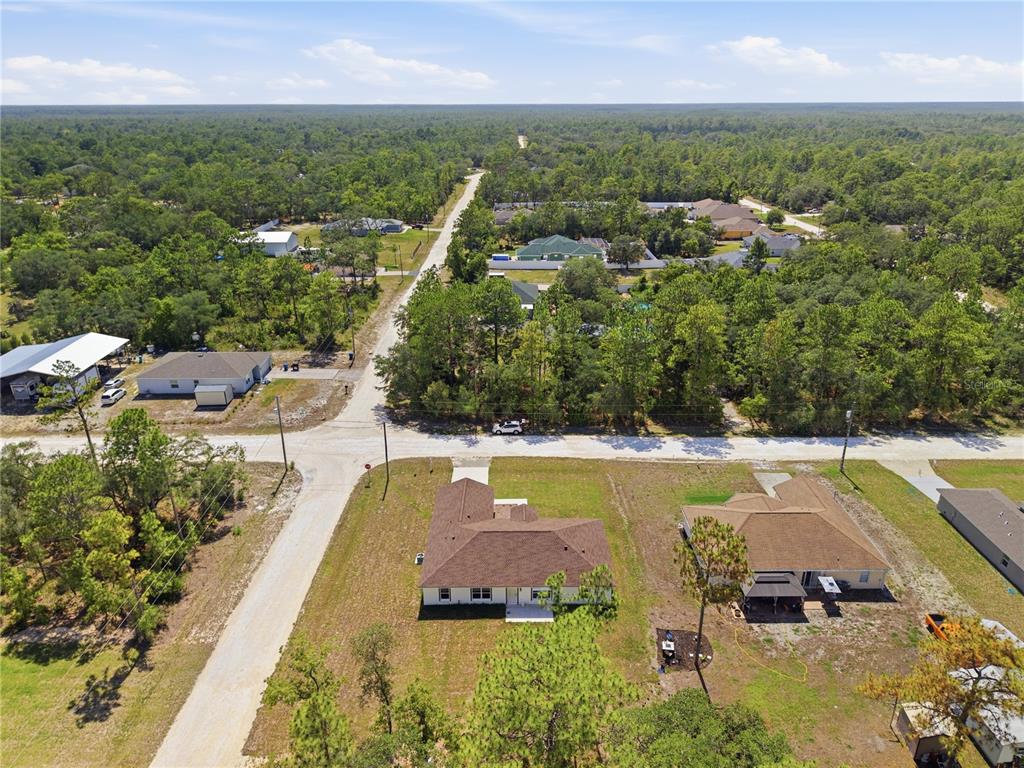 An aerial view shows two houses on a corner lot surrounded by dense forest — 14586 MOCKING WREN ROAD, WEEKI WACHEE, FL