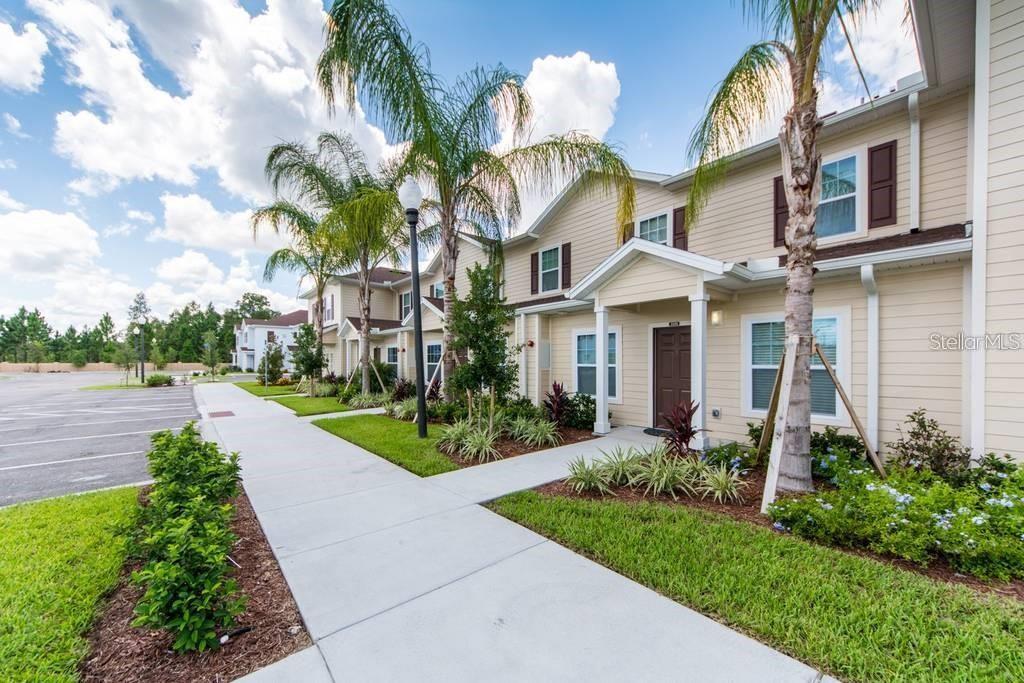 A two-story tan apartment building with a sidewalk, palm trees, and a parking lot — 3226 WISH AVENUE, KISSIMMEE, FL