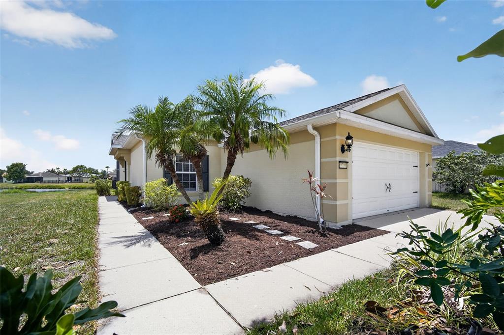 A single-story house with a white garage, tan stucco walls, and palm trees in front — 9780 50TH STREET CIRCLE E, PARRISH, FL
