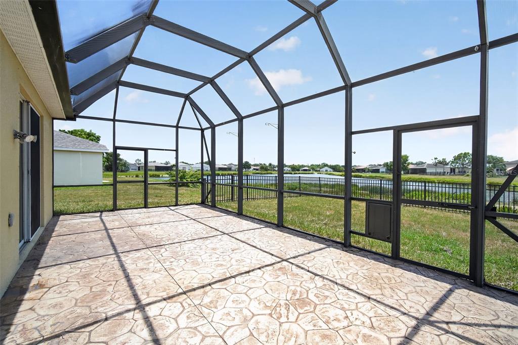 A screened-in patio with a stamped concrete floor overlooks a lake and neighboring houses — 9780 50TH STREET CIRCLE E, PARRISH, FL