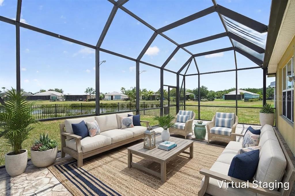 A screened-in patio features outdoor furniture on a rug overlooking a grassy yard and pond — 9780 50TH STREET CIRCLE E, PARRISH, FL