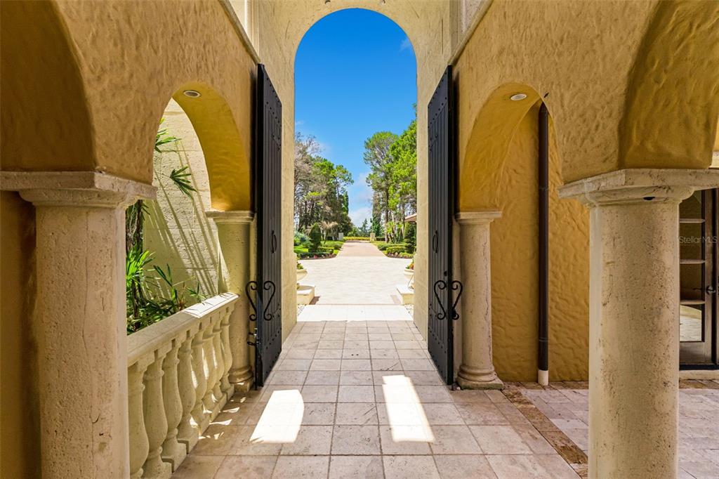 A stone-tiled entryway features arched openings, decorative columns, and large black doors leading outdoors — 16619 AREZO COURT, MONTVERDE, FL