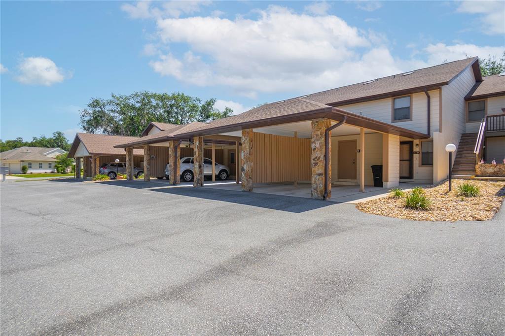 A row of townhomes with covered carports and stone pillars sits beside an asphalt parking lot — 270 E GLASSBORO COURT UNIT 2B, HERNANDO, FL