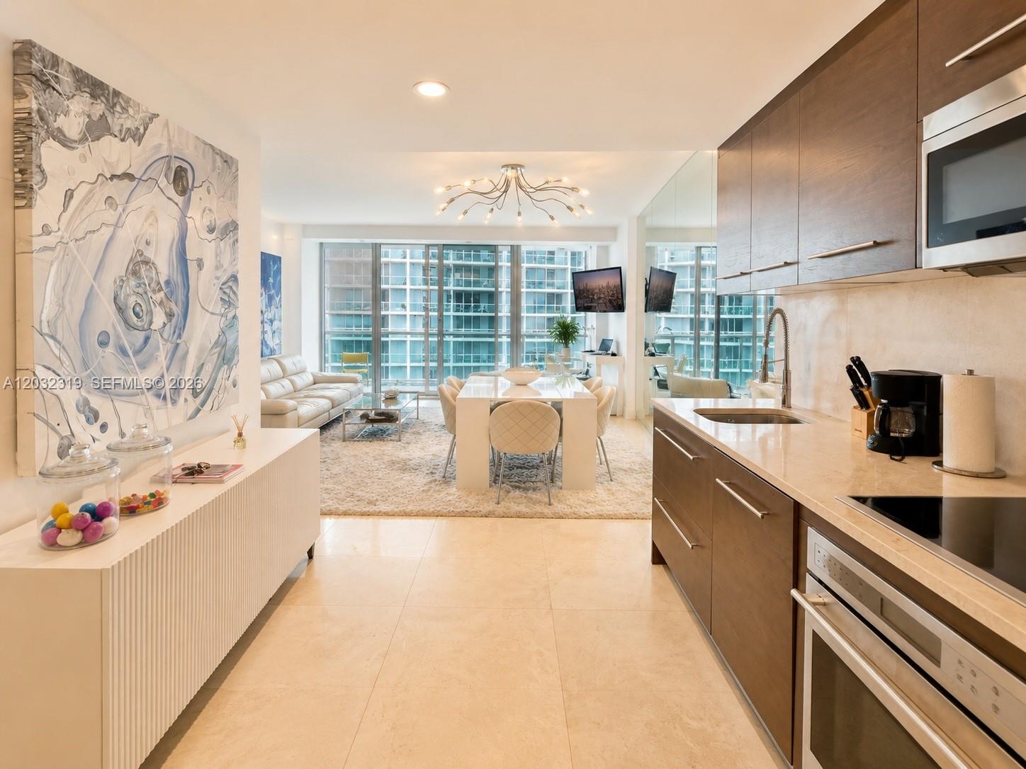 A modern kitchen with dark wood cabinets and stone countertops overlooks a bright dining area — 495 Brickell Ave # 3206, Miami FL 33131, MIAMI, FL