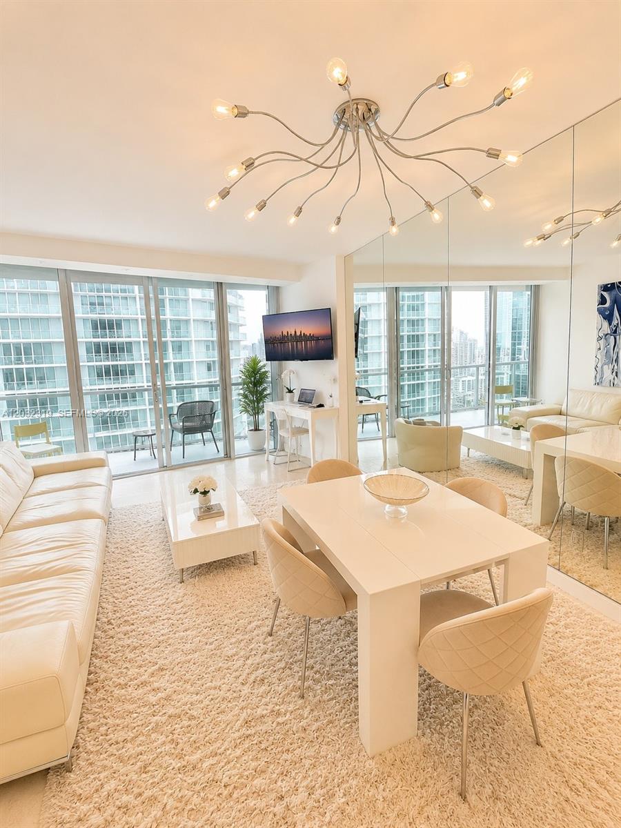 A bright living and dining room features white furniture, a textured rug, and floor-to-ceiling windows — 495 Brickell Ave # 3206, Miami FL 33131, MIAMI, FL