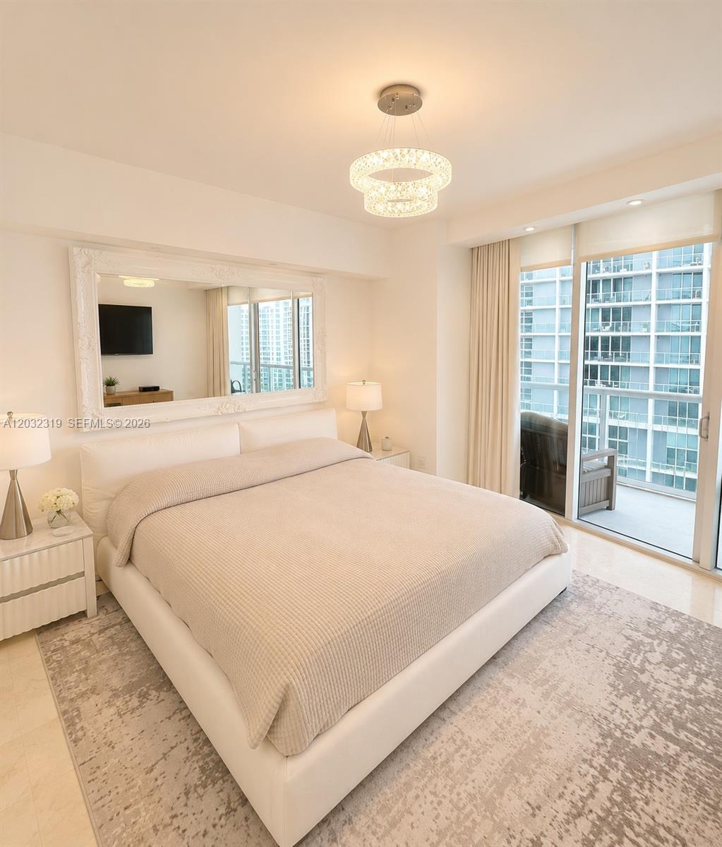 A modern bedroom features a white upholstered bed, a large mirror, and a balcony view — 495 Brickell Ave # 3206, Miami FL 33131, MIAMI, FL