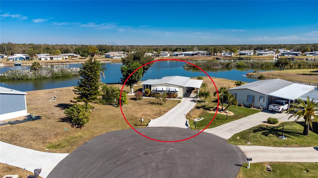 An aerial view shows a single-story house with a driveway and carport near a lake — 1300 SANDERLING DRIVE, ENGLEWOOD, FL