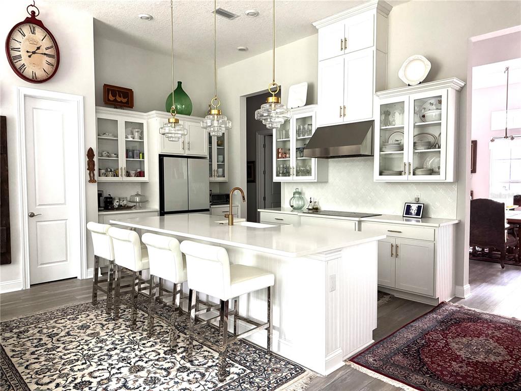 A bright kitchen features white cabinetry, a large central island with seating, and pendant lighting — 862504 N HAMPTON CLUB WAY, FERNANDINA BEACH, FL
