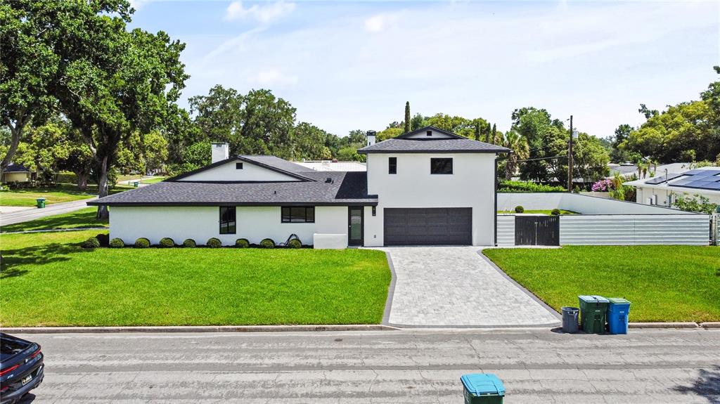 A modern, white single-story house with a dark roof, garage, and paved driveway — 2491 LAUDER DRIVE, MAITLAND, FL