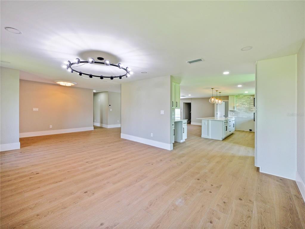 An open-concept living area features light wood flooring, a modern chandelier, and a white kitchen — 2491 LAUDER DRIVE, MAITLAND, FL