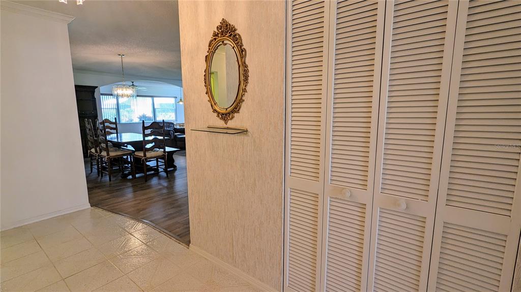 A hallway with a mirror and glass shelf leads to a dining room with wood flooring — 1624 LAYTON COURT UNIT 1624, SUN CITY CENTER, FL