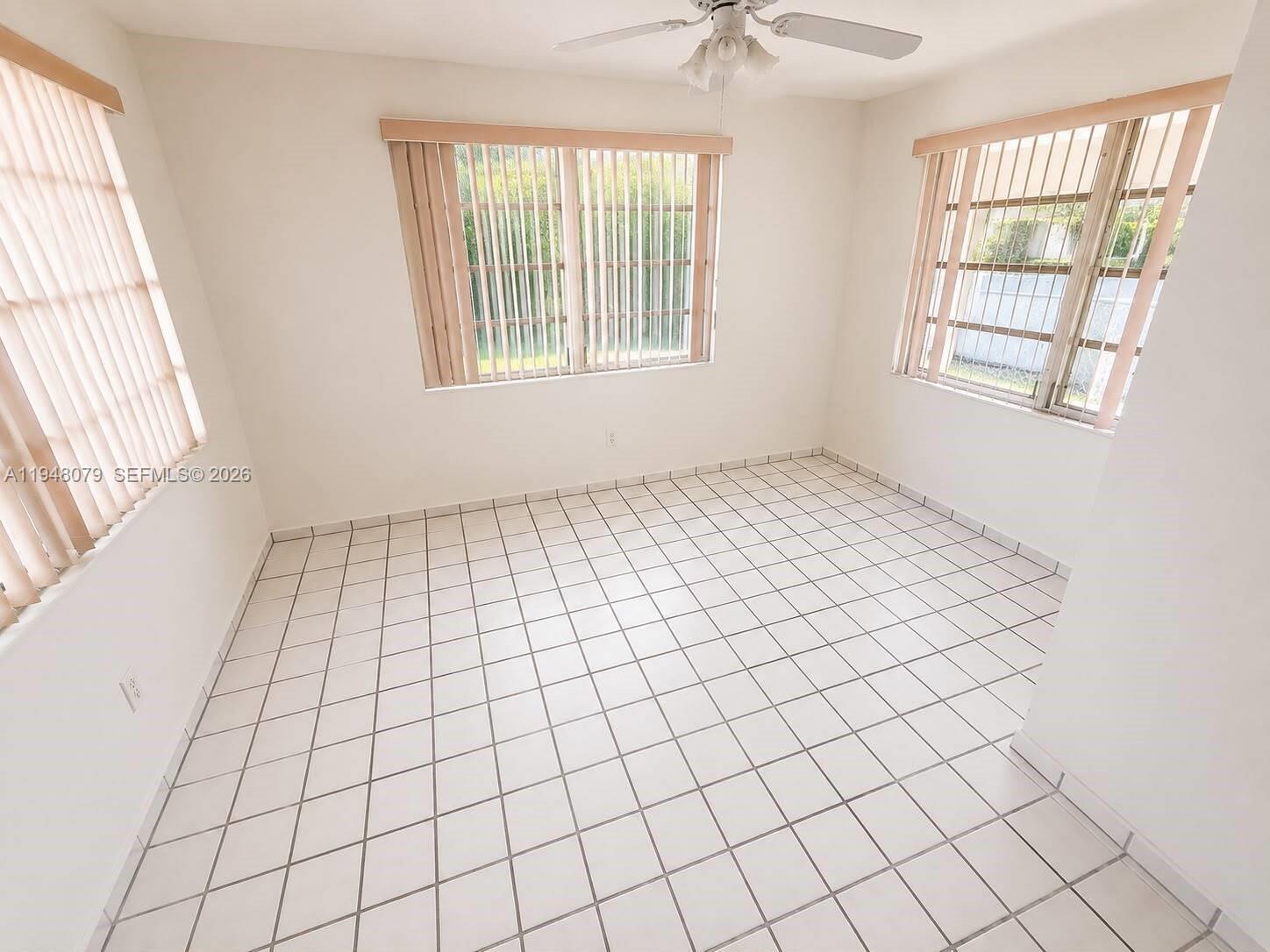 An empty room features white tiled floors, white walls, and three windows with vertical blinds — 5181 NW 5th St, Miami FL 33126, MIAMI, FL