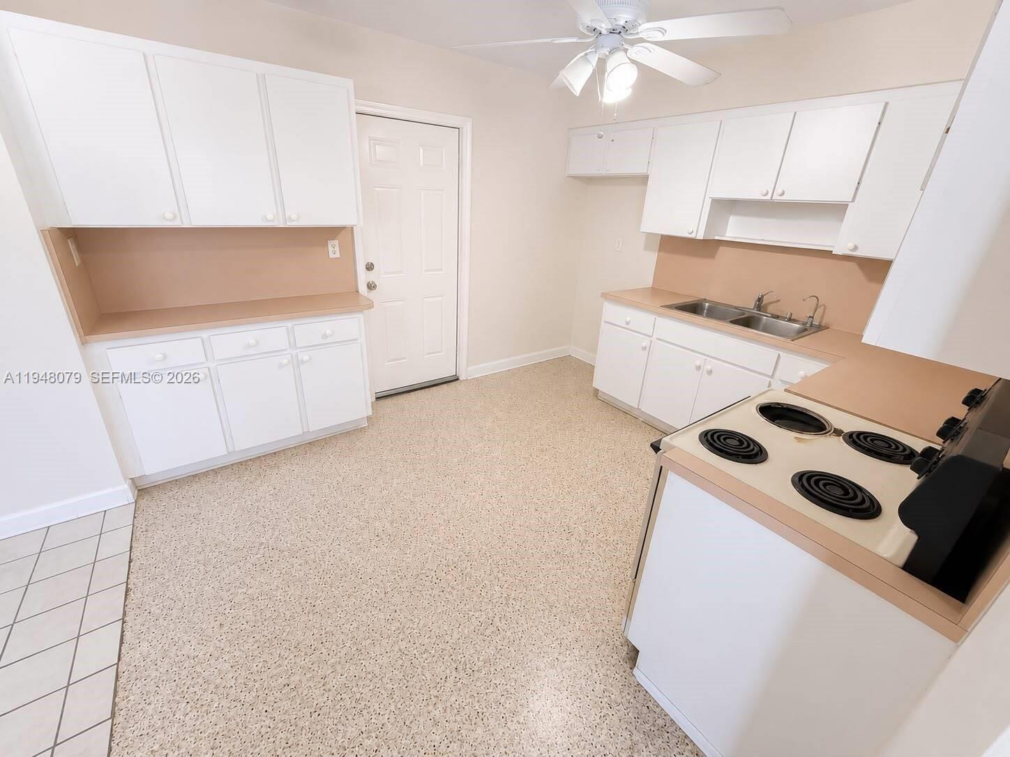 A kitchen features white cabinets, tan countertops, a double sink, and a white stove — 5181 NW 5th St, Miami FL 33126, MIAMI, FL