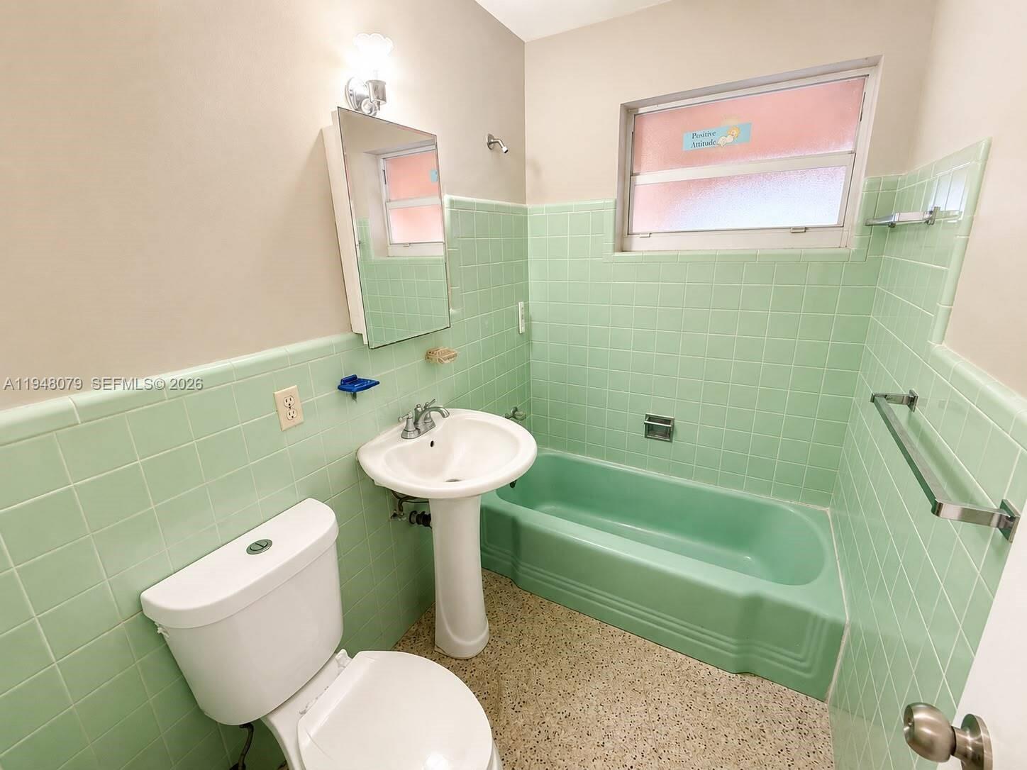 A bathroom features mint green wall tiles, a matching tub, a pedestal sink, and terrazzo flooring — 5181 NW 5th St, Miami FL 33126, MIAMI, FL