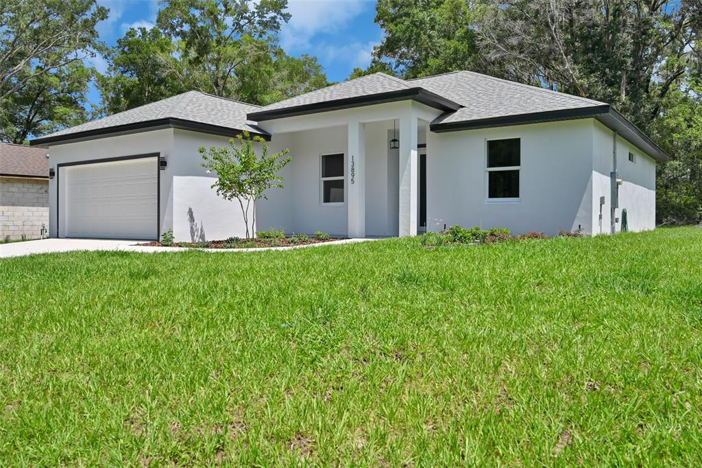 A single-story white house with a two-car garage and a covered front entryway — 13895 SW 110TH PLACE, DUNNELLON, FL