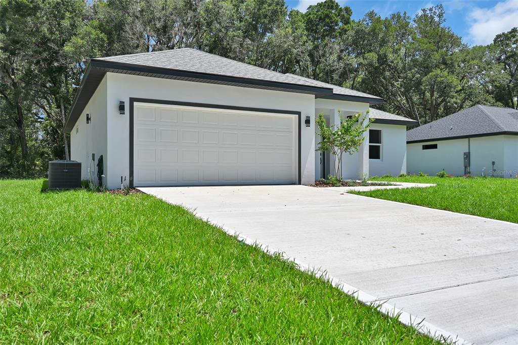 A white single-story house with a two-car garage and a concrete driveway — 13895 SW 110TH PLACE, DUNNELLON, FL