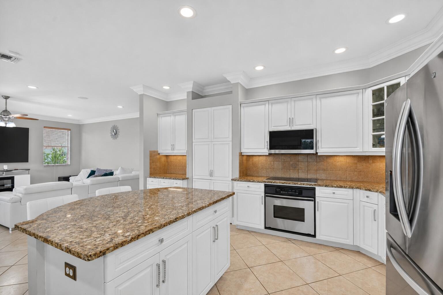 A kitchen with white cabinets, granite countertops, a center island, and tile flooring — 2214 Ridgewood Circle, Royal Palm Beach FL 33411, ROYAL PALM BEACH, FL