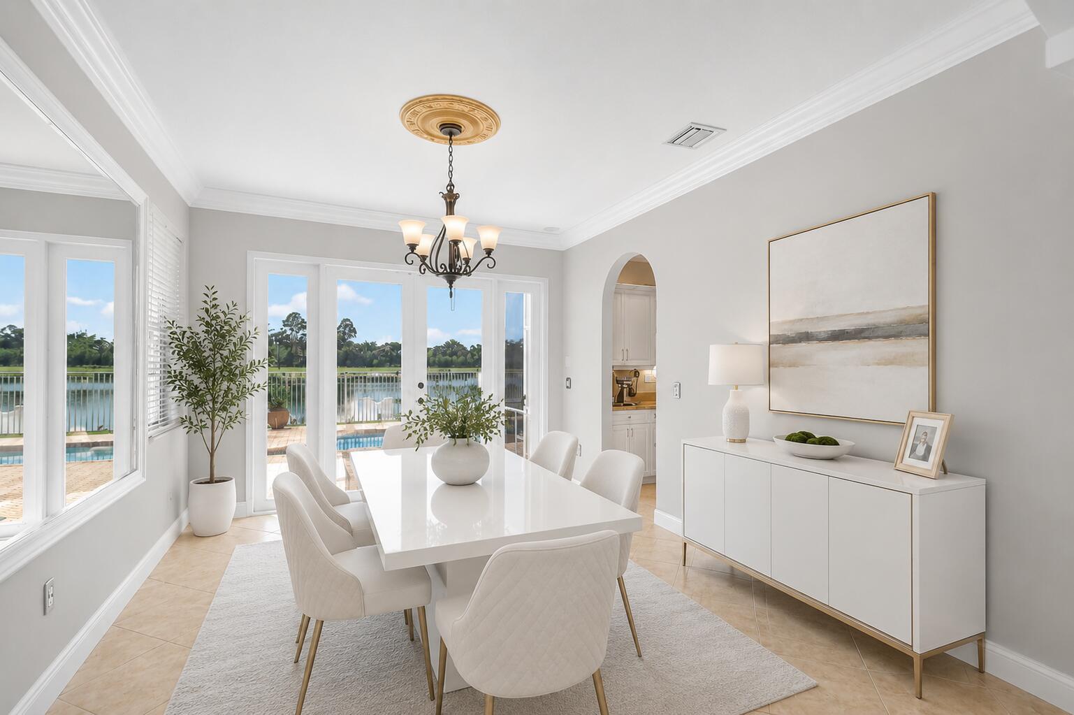 A dining room features a white table, upholstered chairs, a chandelier, and a lake view — 2214 Ridgewood Circle, Royal Palm Beach FL 33411, ROYAL PALM BEACH, FL