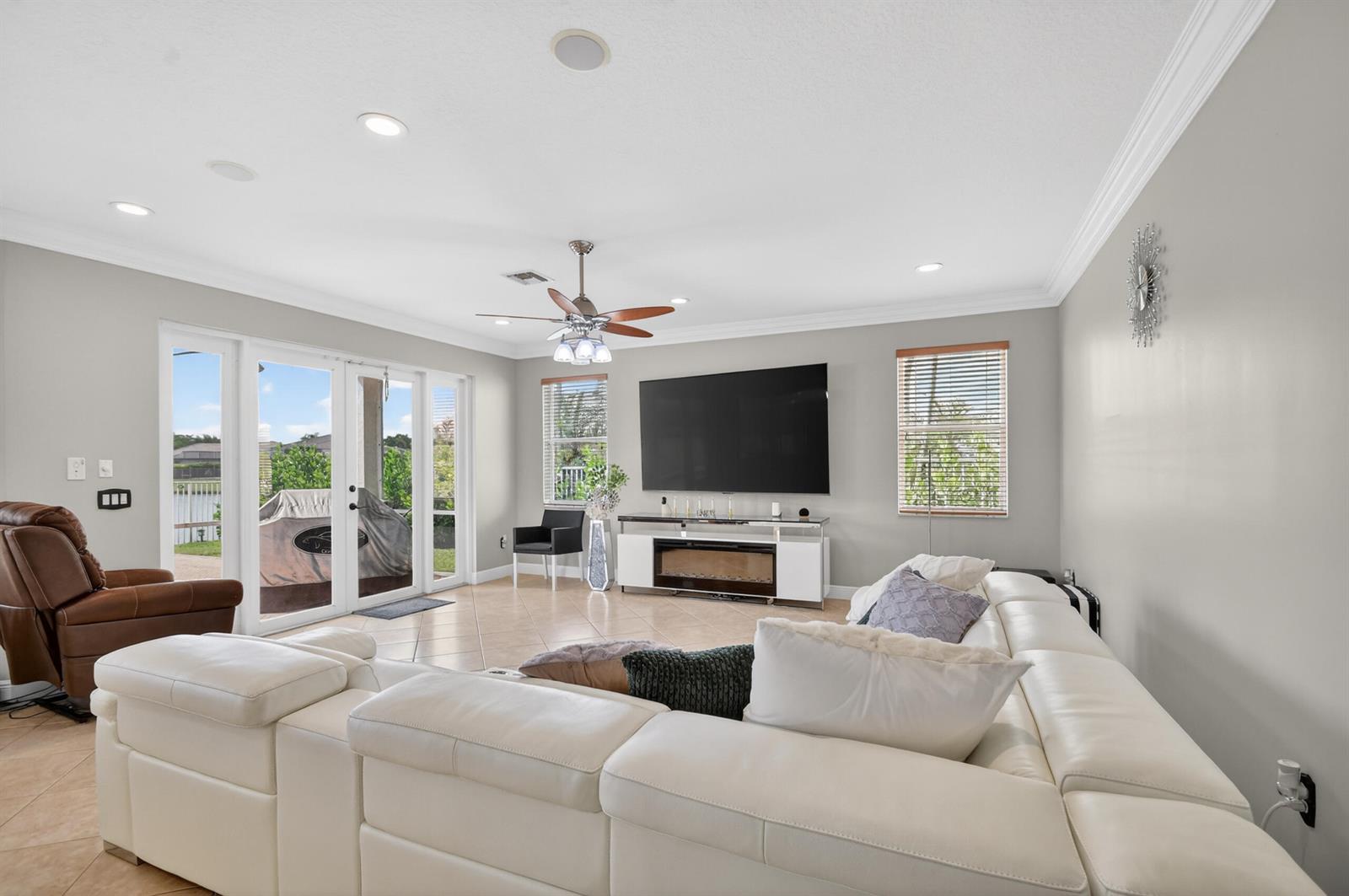 A living room features a white sectional sofa, a large television, and glass patio doors — 2214 Ridgewood Circle, Royal Palm Beach FL 33411, ROYAL PALM BEACH, FL