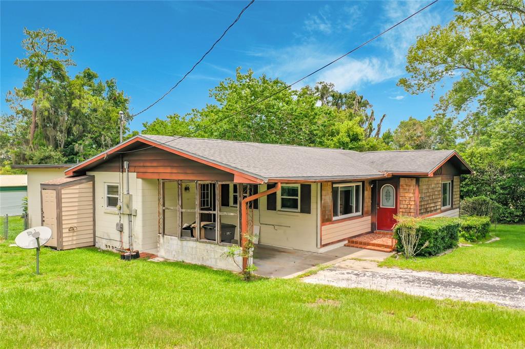 A single-story house with a screened porch, red front door, and a shingled roof — 2405 NE 2ND STREET, OCALA, FL