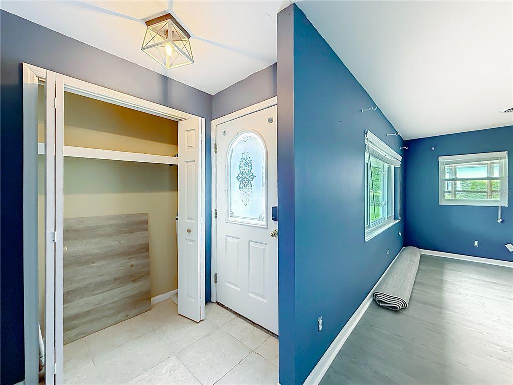 An entryway with a closet, a white front door, and blue walls leads into a room — 2405 NE 2ND STREET, OCALA, FL