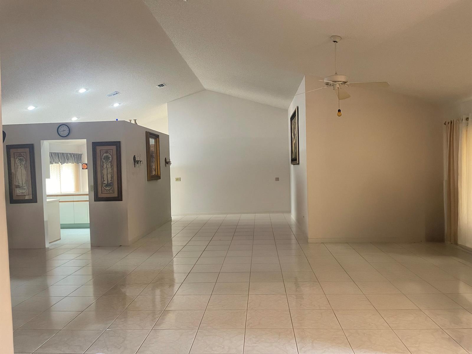 An open-concept living area features vaulted ceilings, white tile flooring, and a central partition wall — 9525 El Clair Ranch Road, Boynton Beach FL 33437, BOYNTON BEACH, FL