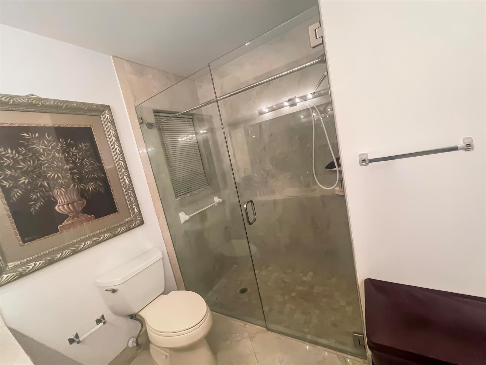 A bathroom features a toilet, a framed wall art piece, and a glass-enclosed walk-in shower — 9525 El Clair Ranch Road, Boynton Beach FL 33437, BOYNTON BEACH, FL