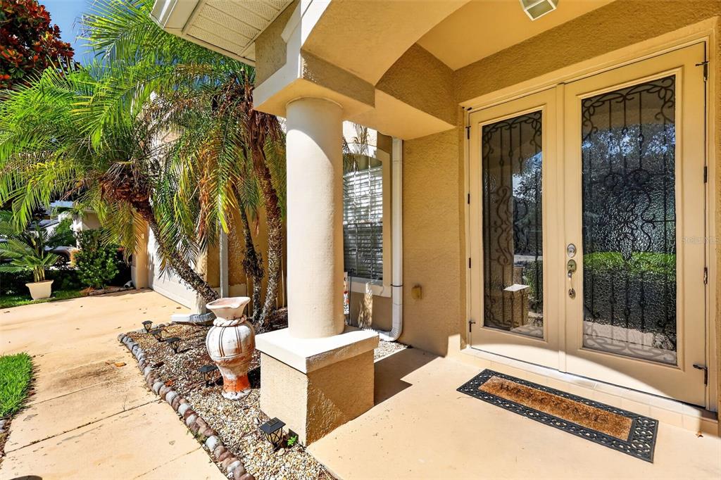 A beige house entrance features double glass doors, a decorative column, and a gravel garden — 1766 OAK GROVE CHASE DRIVE, ORLANDO, FL