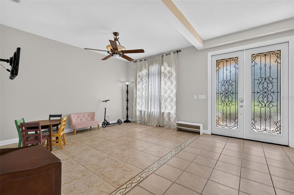 A living room features tile flooring, a ceiling fan, a small dining set, and glass-paned doors — 1766 OAK GROVE CHASE DRIVE, ORLANDO, FL