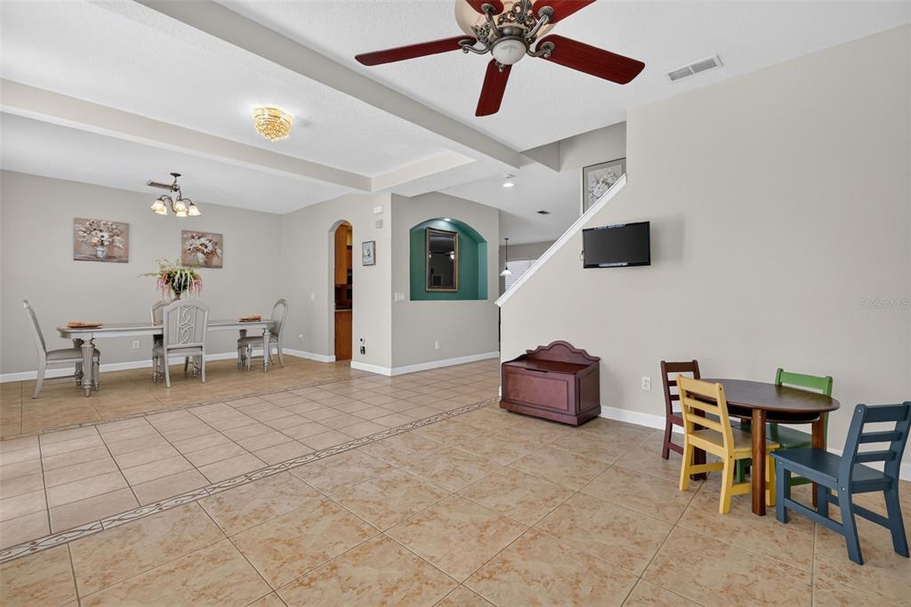 An open-concept dining and living area features tile flooring, a ceiling fan, and stairs — 1766 OAK GROVE CHASE DRIVE, ORLANDO, FL