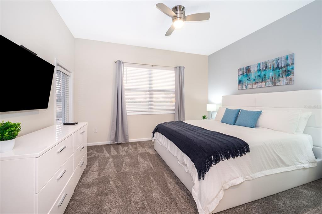A bedroom features a white bed, a white dresser, a ceiling fan, and gray carpet — 817 OCEAN COURSE AVENUE UNIT 817, DAVENPORT, FL