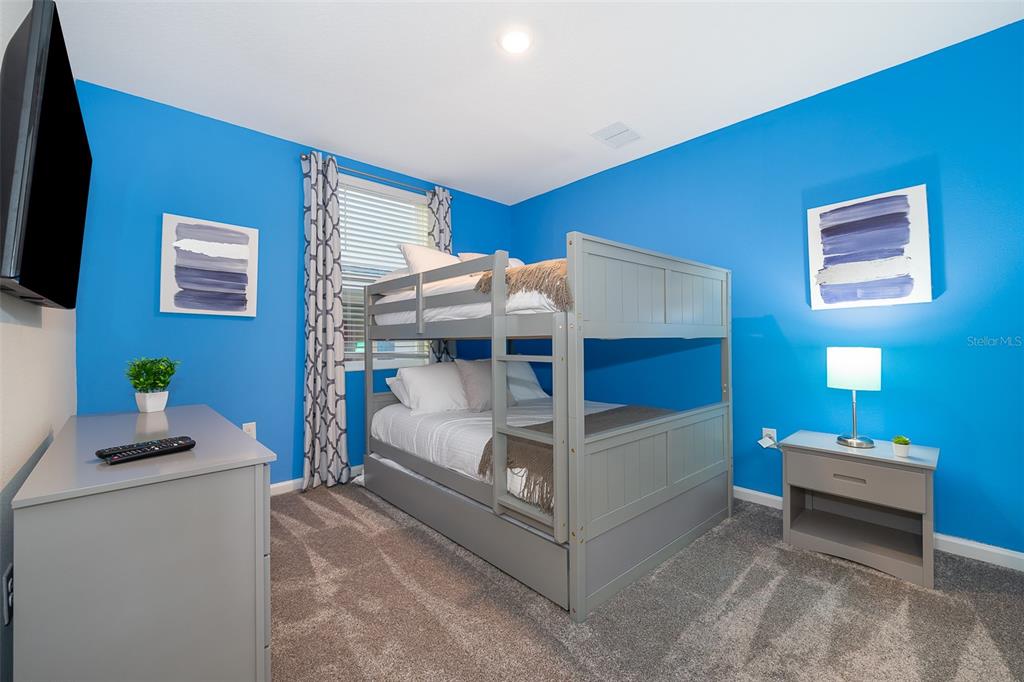 A bedroom features bright blue walls, gray carpet, a gray bunk bed, and a dresser — 817 OCEAN COURSE AVENUE UNIT 817, DAVENPORT, FL