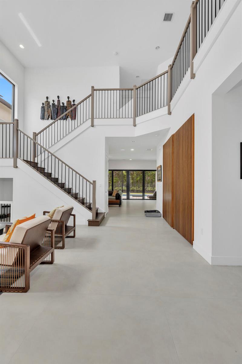 A bright entryway features a staircase with metal railings, light tile floors, and wood paneling — 17347 Sparkling River Road, Boca Raton FL 33496, BOCA RATON, FL