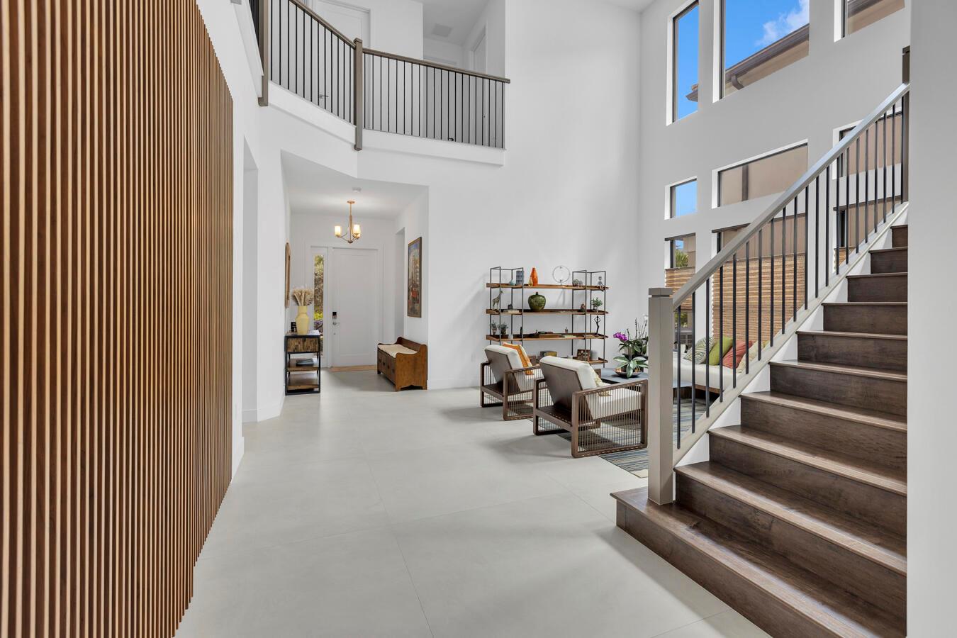 A bright two-story foyer features a slatted wood wall, a staircase, and a seating area — 17347 Sparkling River Road, Boca Raton FL 33496, BOCA RATON, FL