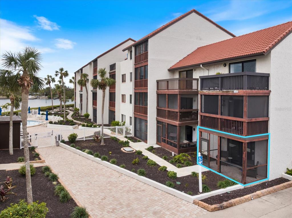 An exterior view of a multi-story apartment building with a highlighted ground-floor screened-in patio — 1604 STICKNEY POINT ROAD UNIT 102, SARASOTA, FL