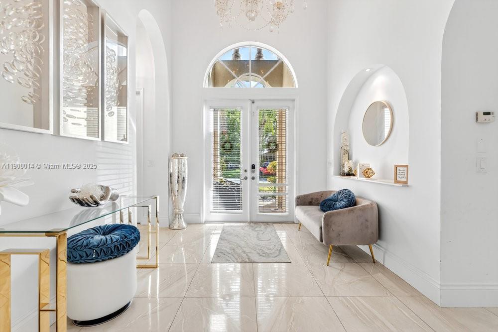 A bright entryway features a double glass door, tiled floors, and a velvet settee — 6313 Paradise Cv, West Palm Beach FL 33411, WEST PALM BEACH, FL