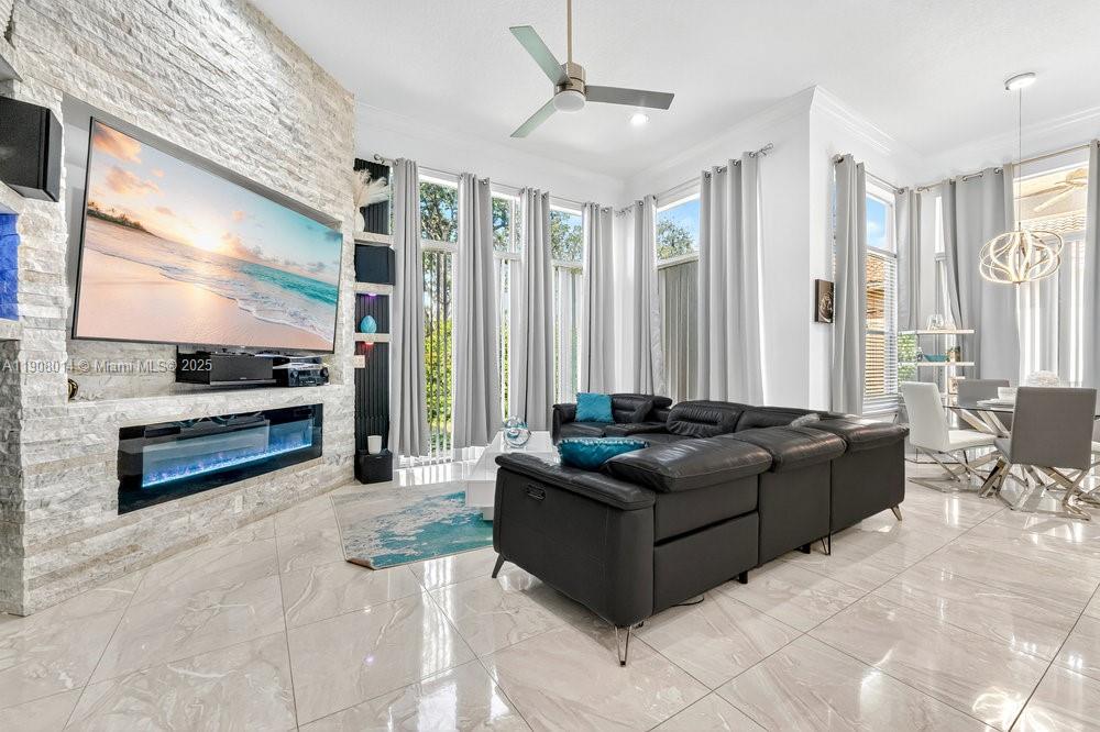A modern living room features a stone accent wall, large television, fireplace, and black sectional — 6313 Paradise Cv, West Palm Beach FL 33411, WEST PALM BEACH, FL