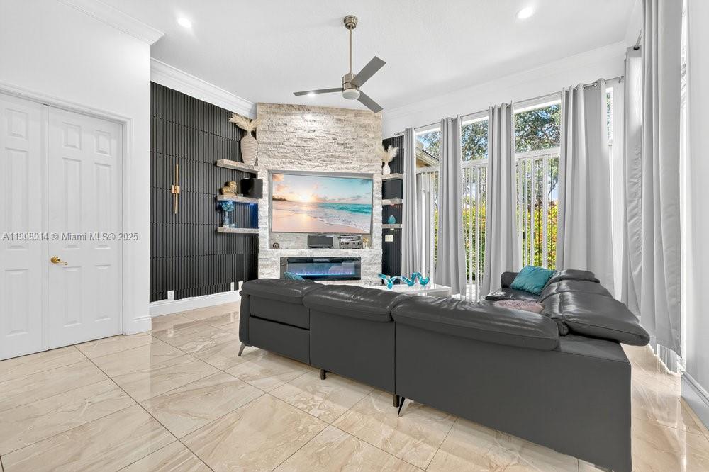 A living room features a stone fireplace, a black slatted wall, and a gray sectional — 6313 Paradise Cv, West Palm Beach FL 33411, WEST PALM BEACH, FL