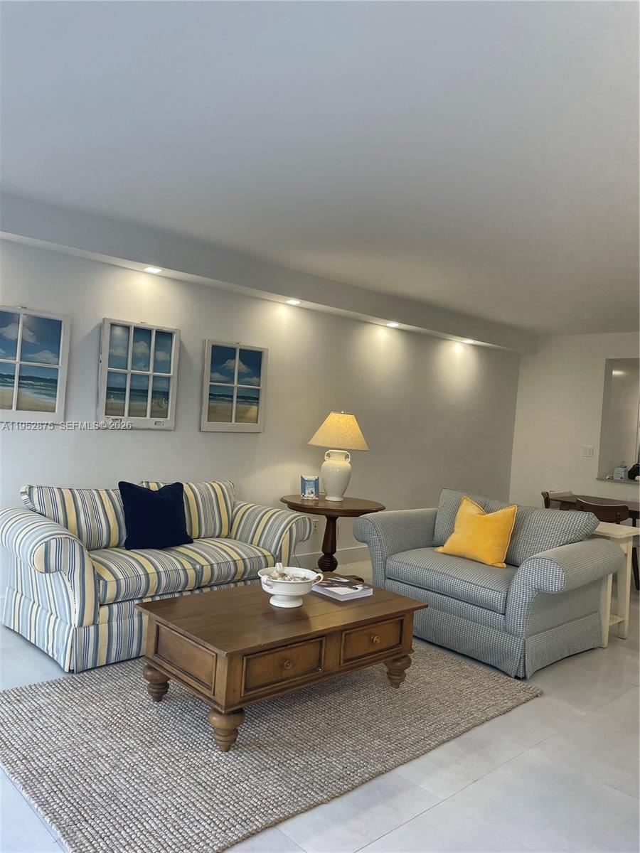 A living room features two sofas, a wooden coffee table, and wall art under recessed lighting — 10275 Collins Ave # 208, Bal Harbour FL 33154, BAL HARBOUR, FL