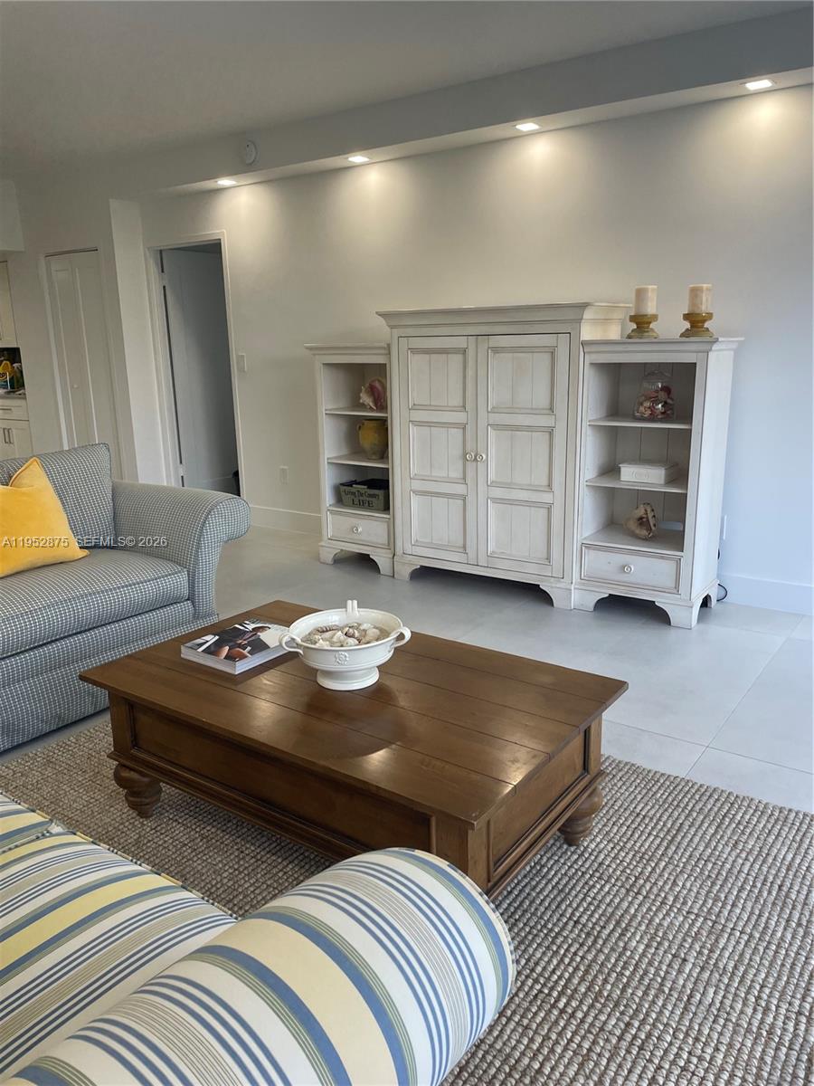 A living room features a wooden coffee table, a white storage unit, and patterned furniture — 10275 Collins Ave # 208, Bal Harbour FL 33154, BAL HARBOUR, FL