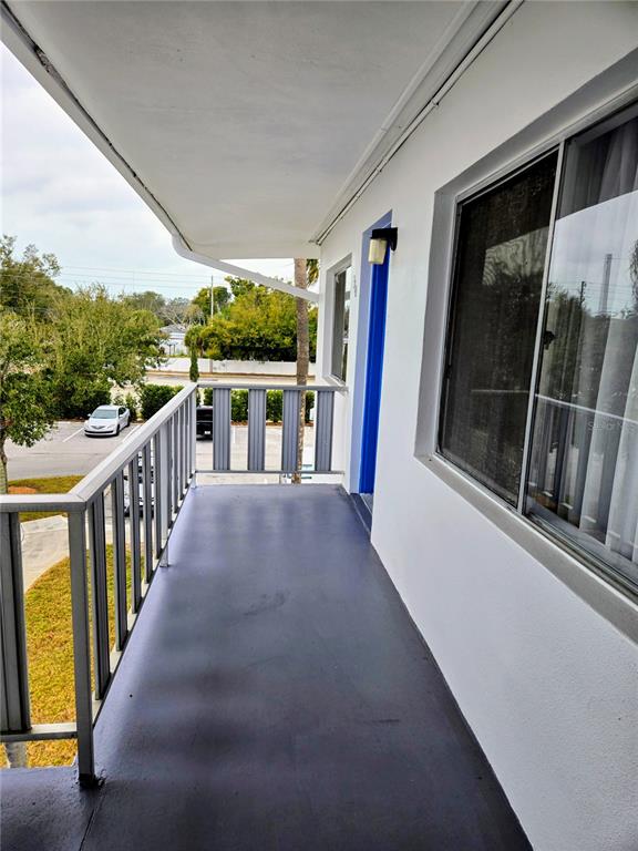 A covered outdoor balcony with gray flooring, a metal railing, and a blue door — 11251 80TH AVENUE UNIT 310, SEMINOLE, FL