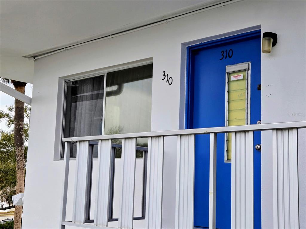 A white exterior wall features a blue door and a window labeled with the number 310 — 11251 80TH AVENUE UNIT 310, SEMINOLE, FL