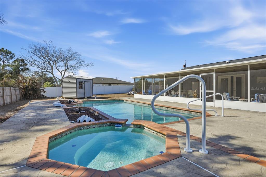 A backyard features a swimming pool, a connected hot tub, and a screened-in patio area — 13380 BARLINGTON STREET, SPRING HILL, FL