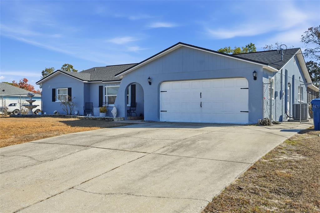 A light blue single-story house with a two-car garage and a concrete driveway — 13380 BARLINGTON STREET, SPRING HILL, FL