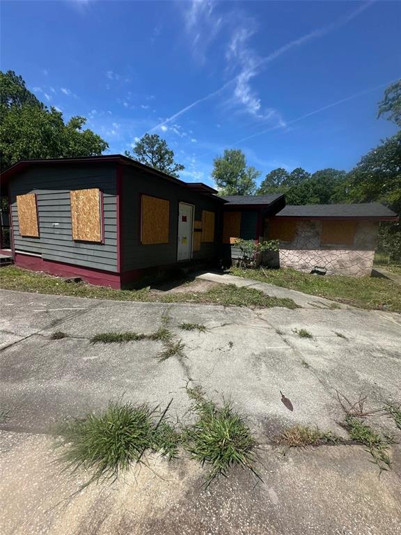 A single-story house with boarded-up windows and a cracked concrete driveway under a blue sky — 5851 DUNMIRE AVENUE, JACKSONVILLE, FL
