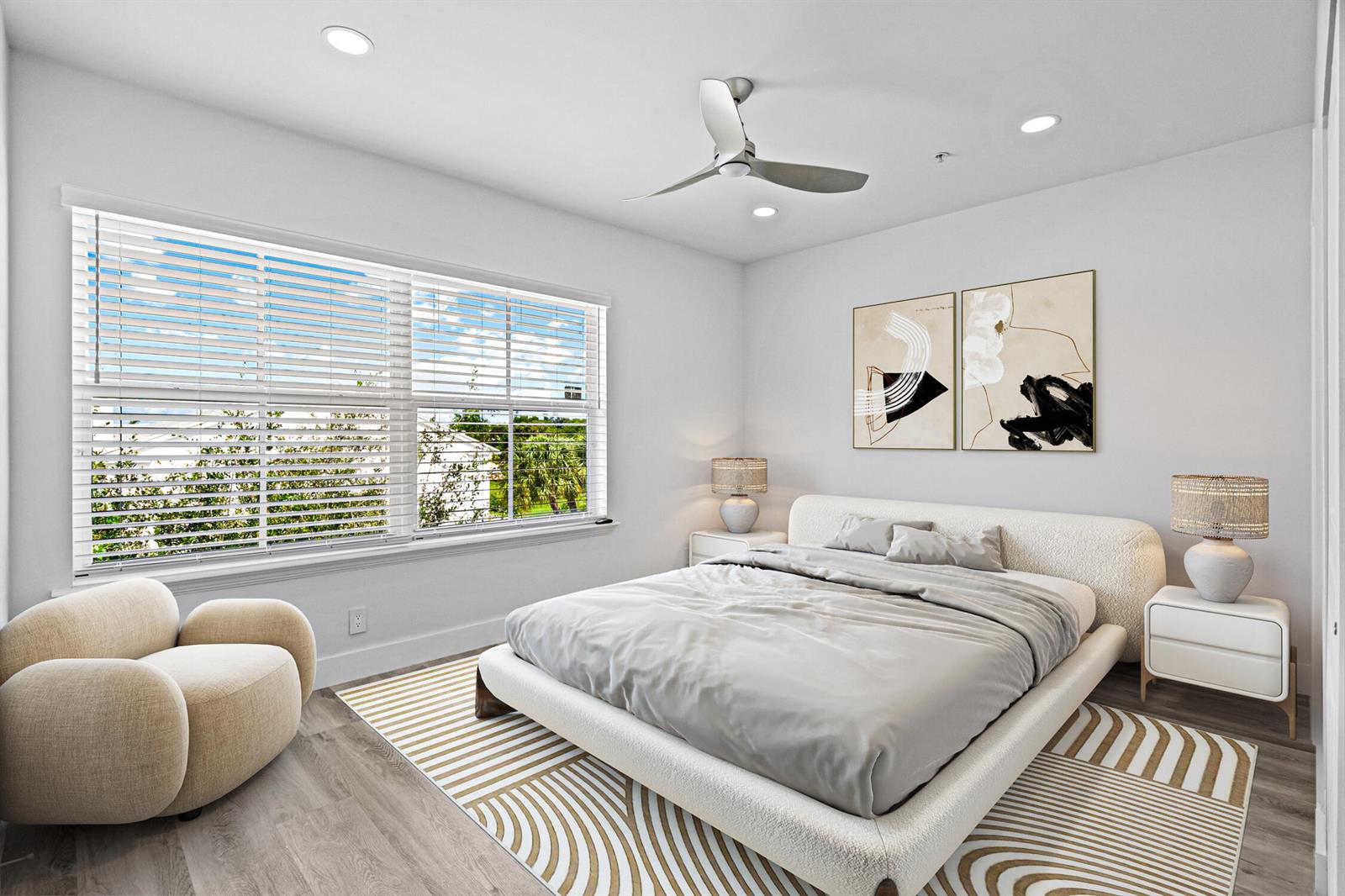 A bedroom features a bed with a white frame, a patterned rug, and a chair — 75 NW 4th Avenue # 75, Delray Beach FL 33444, DELRAY BEACH, FL