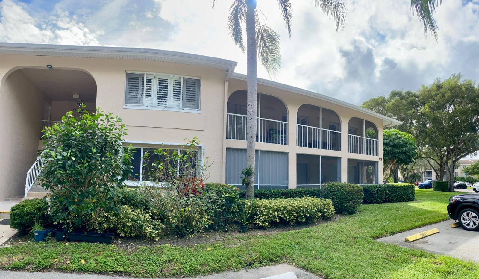 A two-story beige apartment building features arched screened balconies and a landscaped front yard — 13770 Oneida Drive # B2, Delray Beach FL 33446, DELRAY BEACH, FL