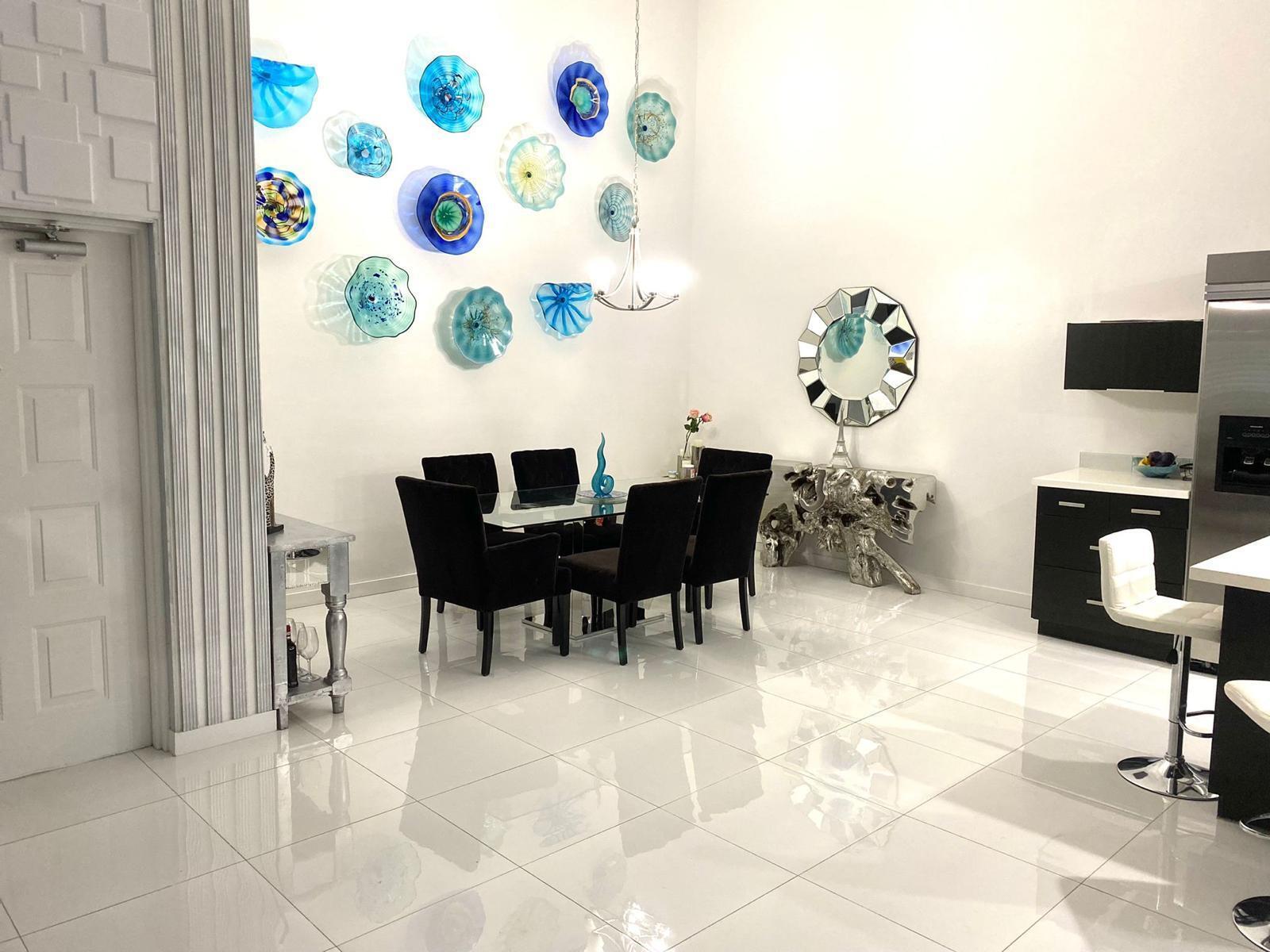 A dining room features a glass table, black chairs, and blue glass wall art — 13770 Oneida Drive # B2, Delray Beach FL 33446, DELRAY BEACH, FL